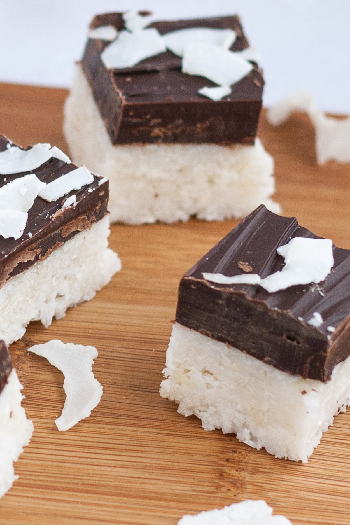 Squares of coconut bars covered in a layer of chocolate.