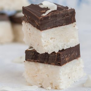 Stack of two coconut bars covered in a layer of chocolate.