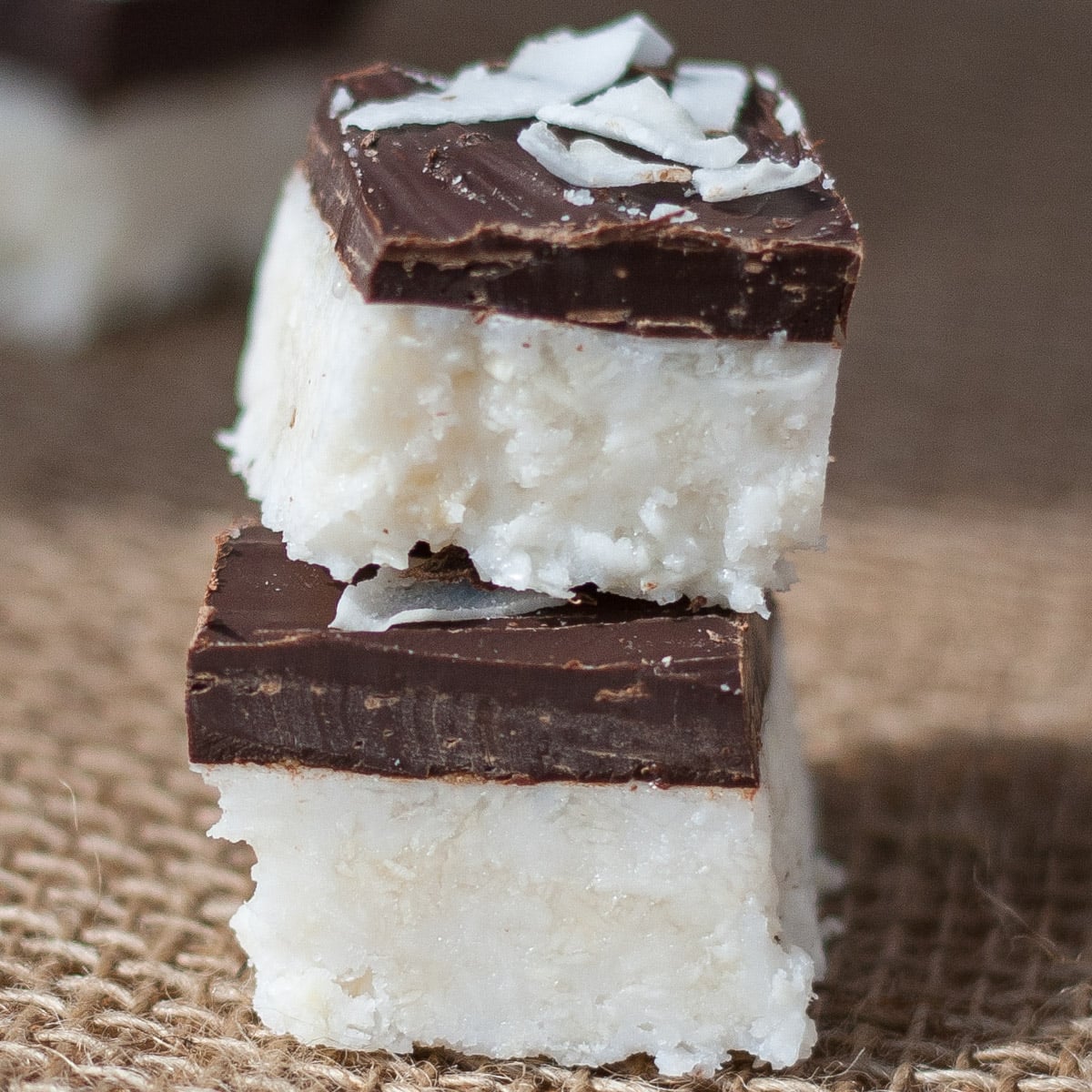 Stack of two coconut bars covered in a layer of chocolate.