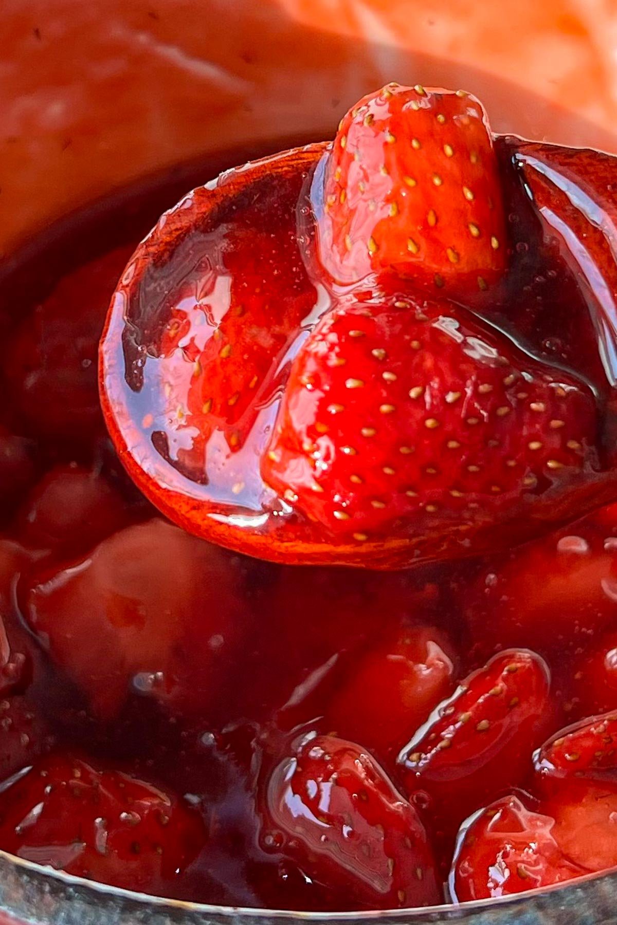 Chunky strawberry sauce in saucepan with wooden spoon.