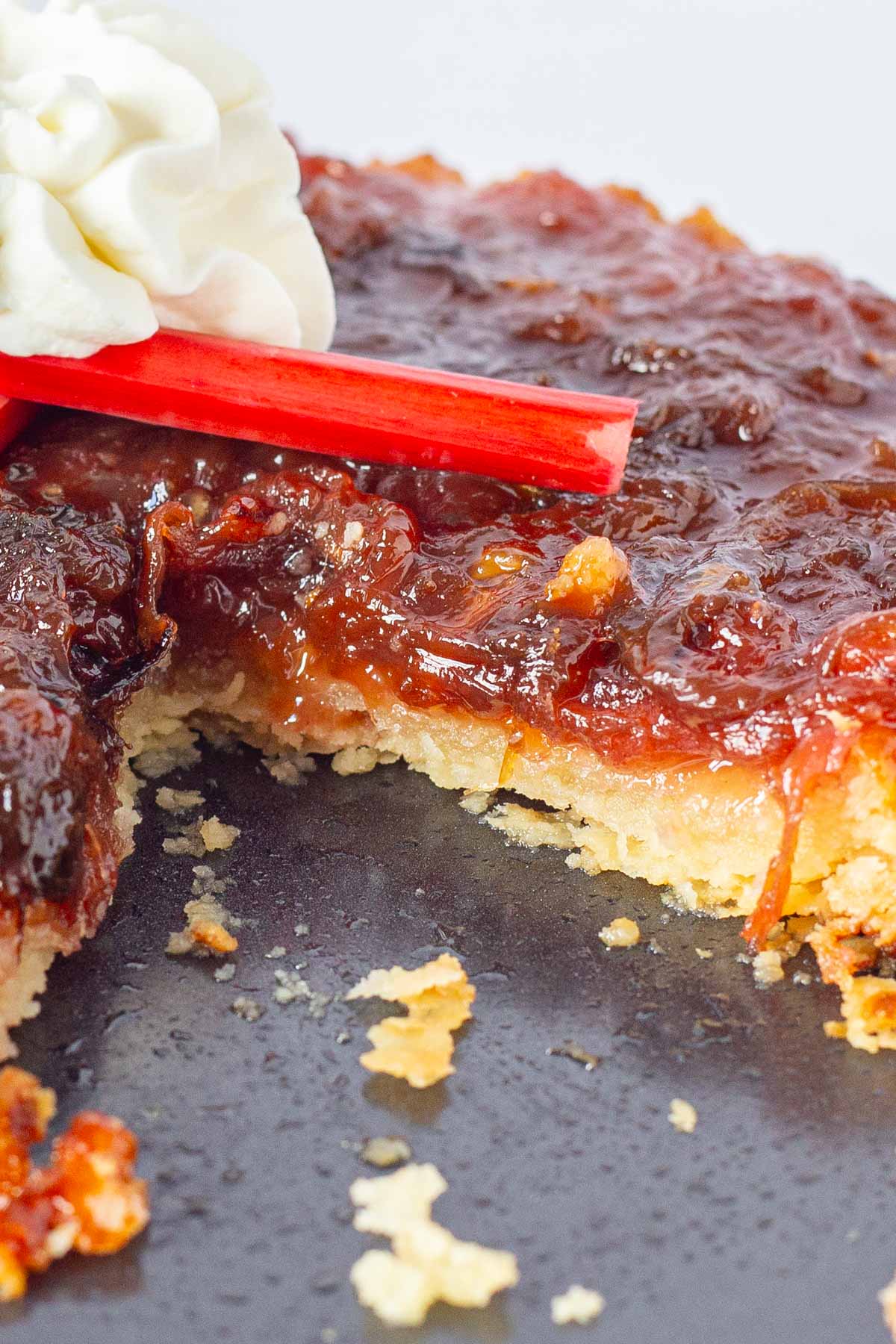 Tart made with rhubarb, topped with whipped cream and fresh rhubarb stems.