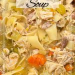 A hearty turkey noodle soup with chunks of turkey, carrots, celery and egg noodles served with copper ladle.