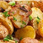 Roasted baby potatoes with crispy skins, garnished with chopped green onions and parsley.
