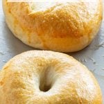 Freshly baked bagels with a golden, glossy crust on a baking tray.
