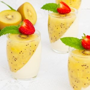 Elegant dessert glasses filled with creamy panna cotta, topped with a diagonal layer of kiwi puree. Garnished with fresh strawberries and mint leaves