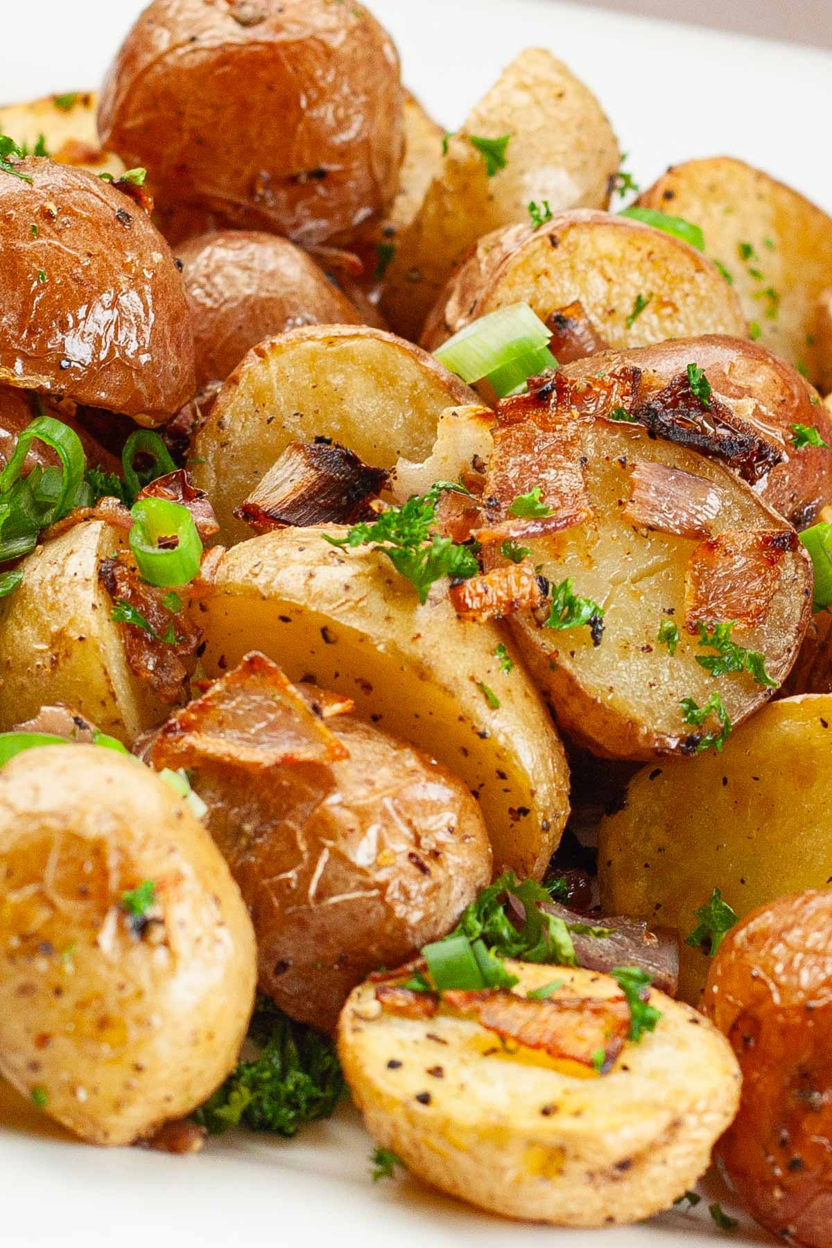 Roasted baby potatoes with crispy skins, garnished with chopped green onions and parsley.