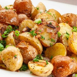 Roasted baby potatoes with crispy skins, garnished with chopped green onions and parsley.