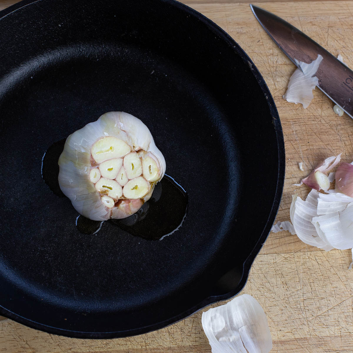 Head of garlic with the top sliced off roasted in a cast iron pan.