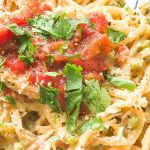 Plate of chicken and linguine tossed in creamy sauce, topped with salsa and cilantro.