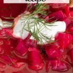 Bowl of chunky borscht soup topped with dollop of sour cream and a sprig of dill.