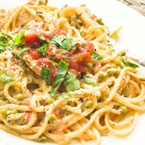 Plate of chicken and linguine tossed in creamy sauce, topped with salsa and cilantro.