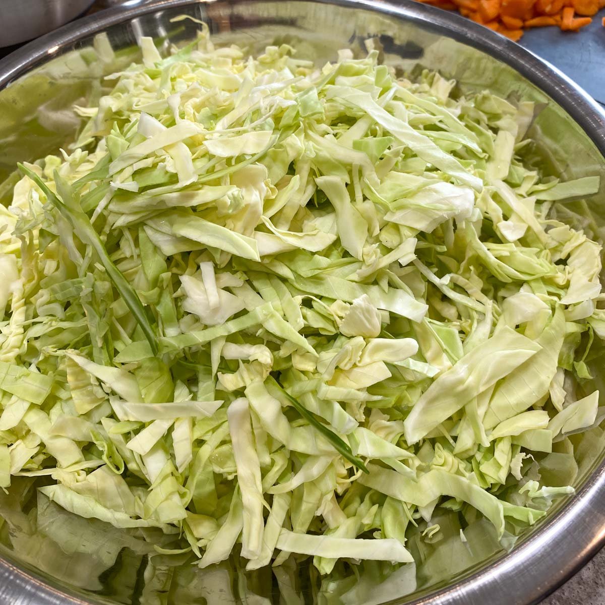 Shredded cabbage in stainless steel bowl.