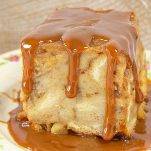 Bread pudding square drenched in glossy caramel sauce sits on a floral plate.