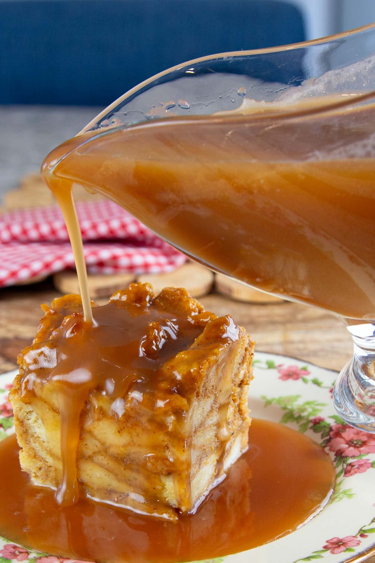Glass serving dish filled with caramel sauce pouring sauce over bread pudding.
