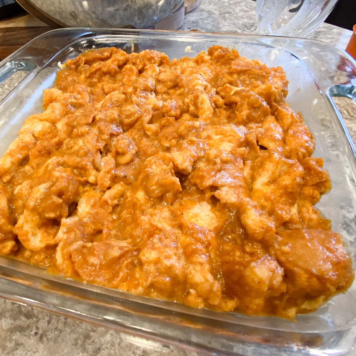 A glass baking dish filled with batter for pumpkin bread pudding.