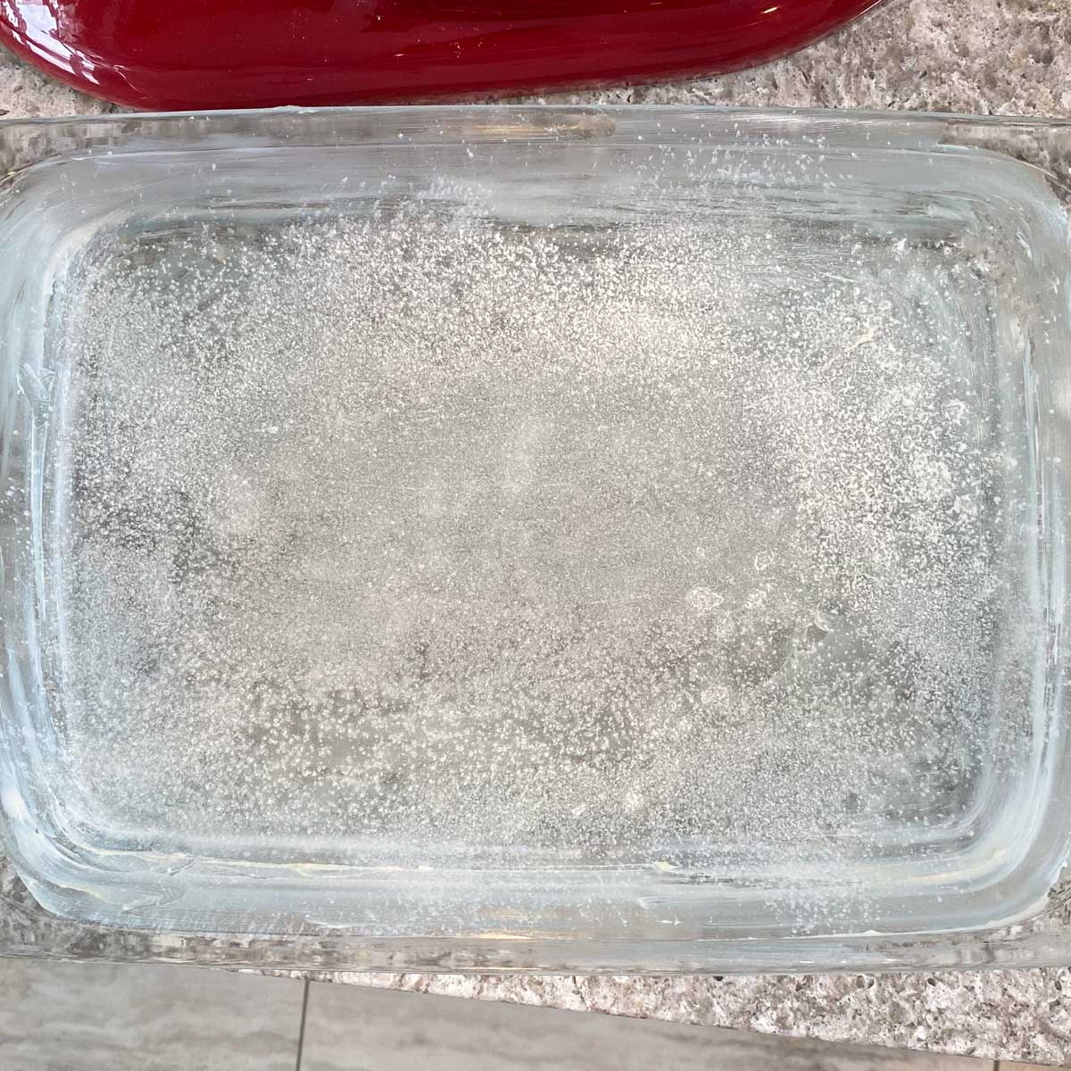 A glass rectangle baking dish lightly dusted with flour.