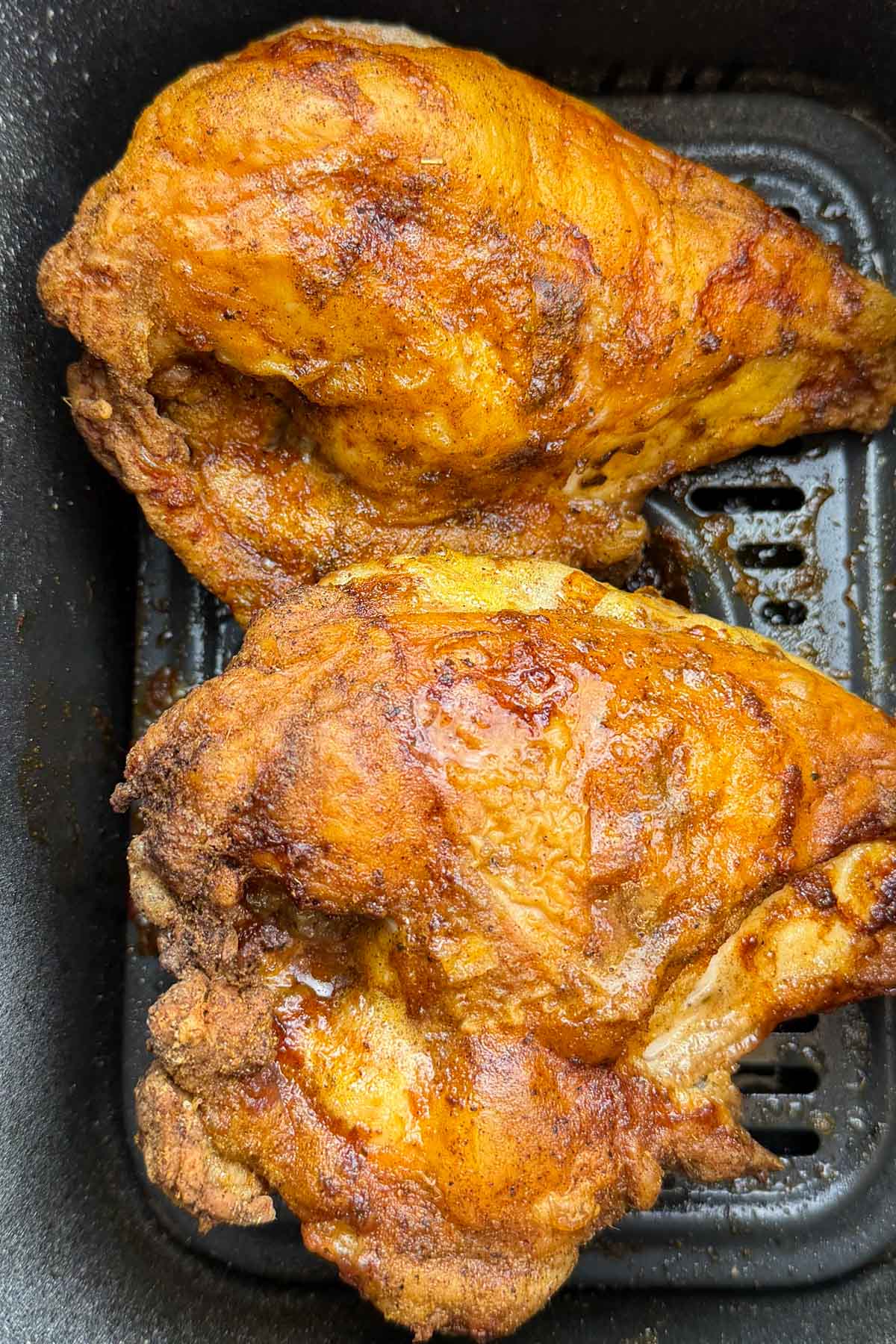 Golden-brown, crispy chicken pieces resting in an air fryer basket.
