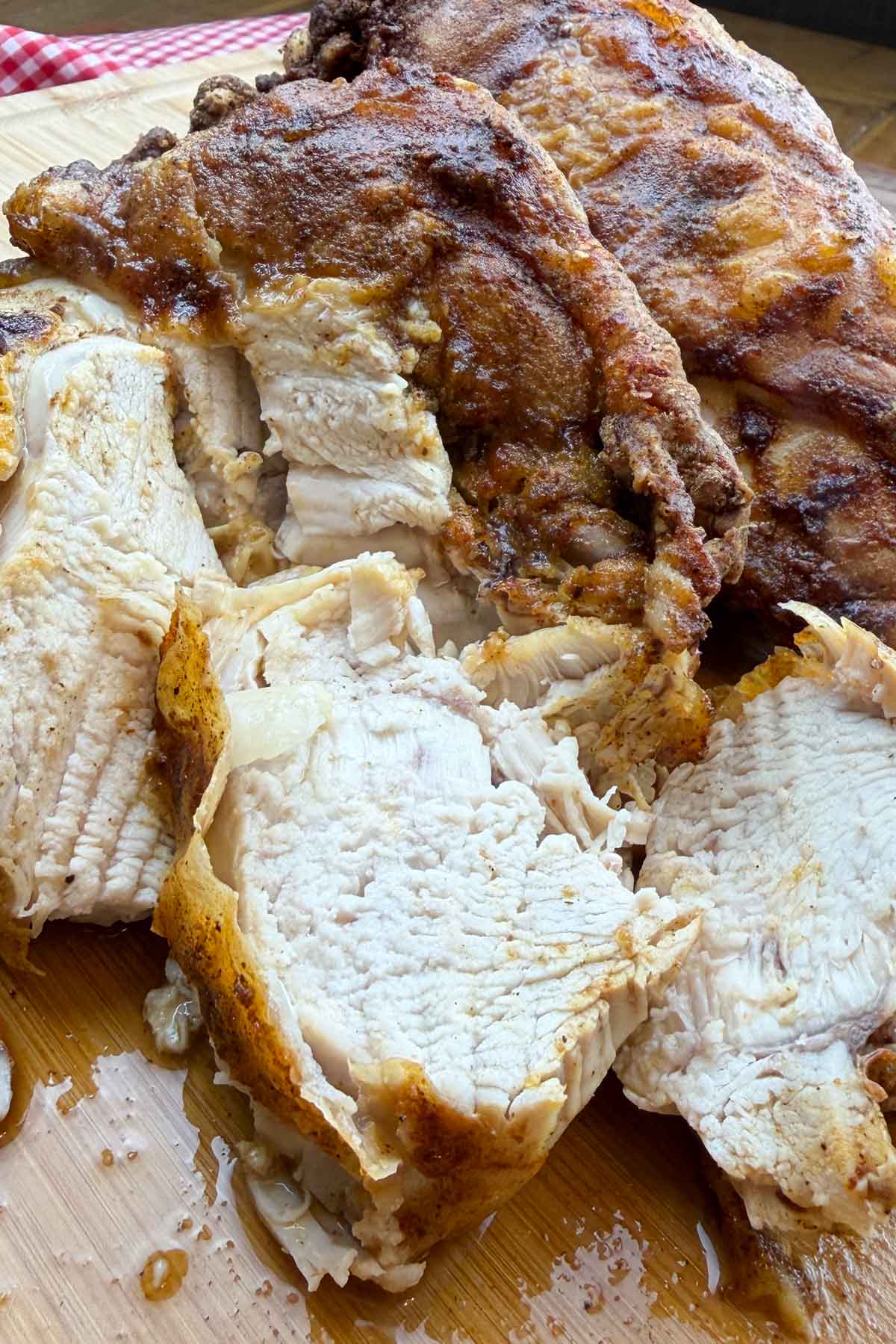 Roasted chicken breasts, golden-brown and juicy, sliced and displayed on a wooden board.