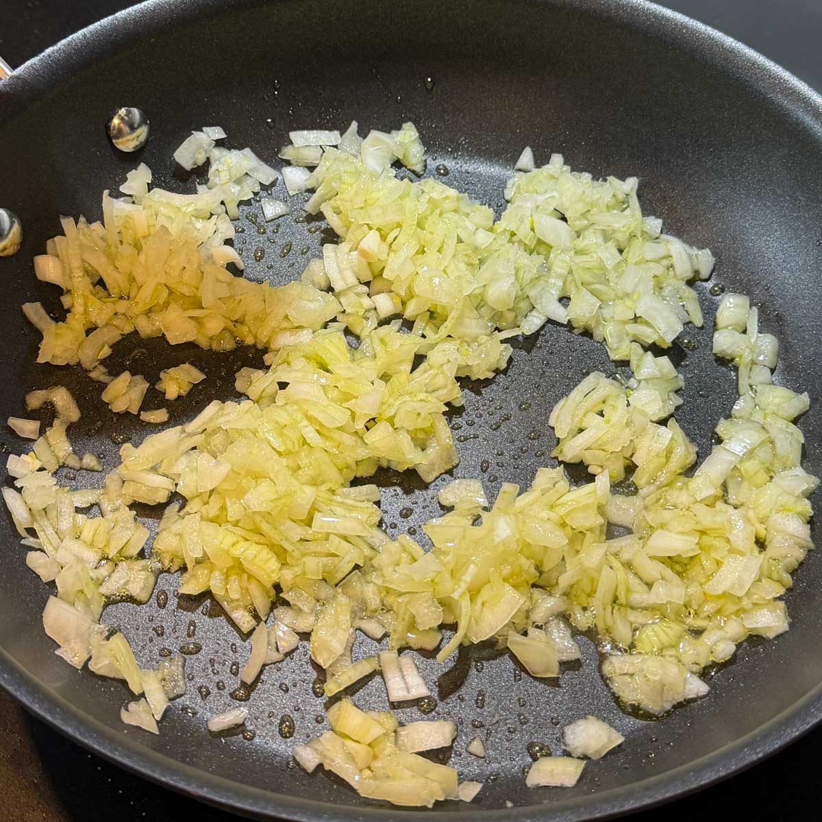 Chopped onions saut&eacute; in a pan with a wooden spoon.