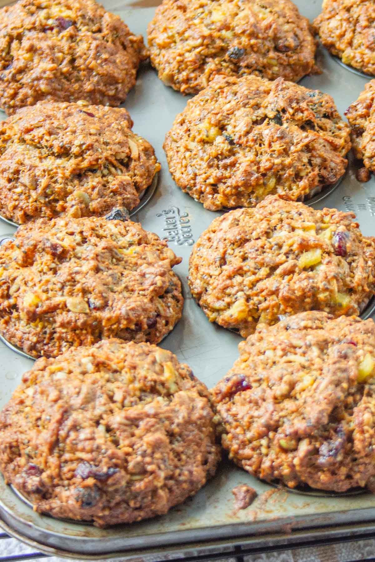 Golden-brown muffins with a textured, crumbly surface, cooling in a muffin tray.