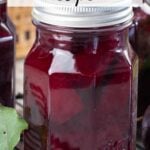 Glass jar of pickled beets on black cooling rack.