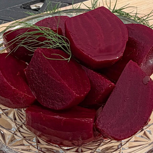 Cut up pickled beets in glass bowl, garnished with fresh dill sprigs.