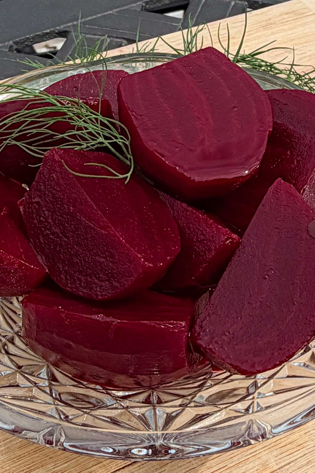 Cut up pickled beets in glass bowl, garnished with fresh dill sprigs.